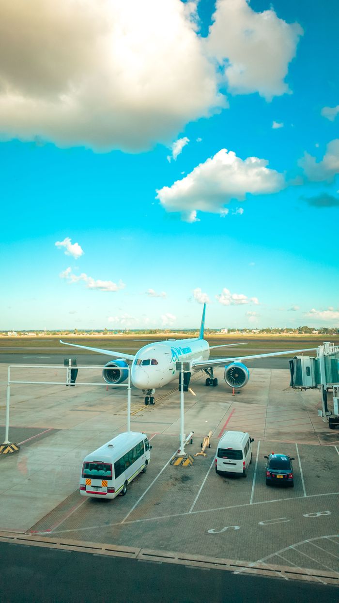 A passenger airplane docked at a gate in Dar es Salaam, Tanzania under a vibrant blue sky.